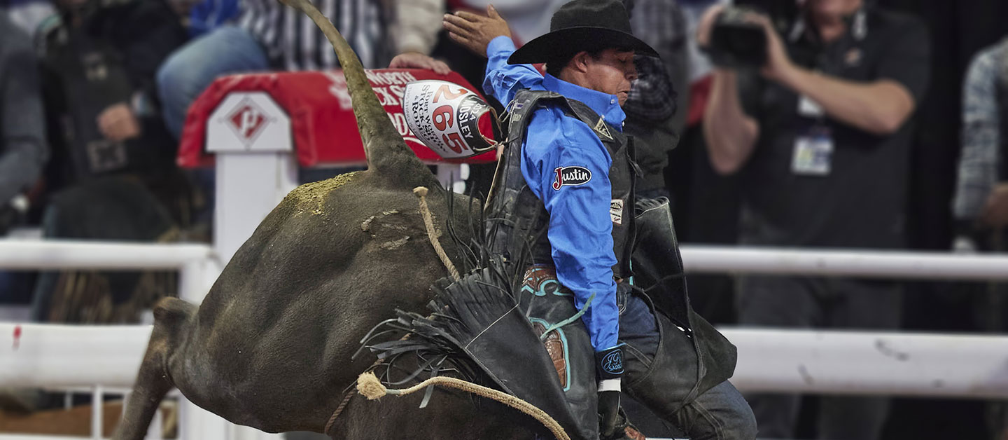 Laramie Mosley riding a black bull with his hand in the air at the Fort Worth Stock Show & Rodeo. 